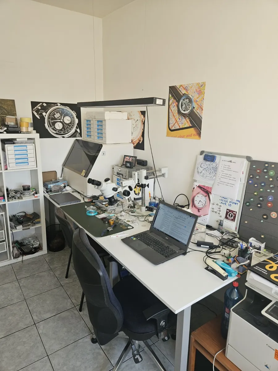 The CONSTANTIME workshop bench in Târgu Mureș, with a stereo microscope, parts trays and watchmaking tools